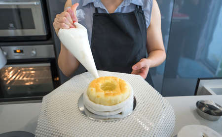 Woman added whipped cream on cake gingerbread dessert homemade bakery in kitchen preparing deliciousの写真素材