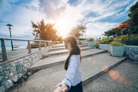 Couple asian lover woman holding hands boyfriend walking together to beach on summer vacation at park man follow girlfriend her guide tourist honeymoon.の写真素材