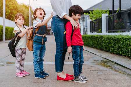 Mother and pupil and kids holding hands going to school in first class with schoolbag or satchel walking to school bus, Parent and son,sister preschool の写真素材