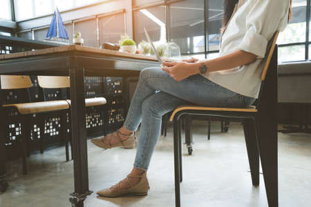 Freelancer woman working using digital laptop computer typing keyboard and drink coffee breakfast on workplace table her resting at cafe shop in the morning.の写真素材