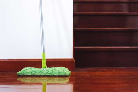 Mop green cleaning equipment of interior on the wooden floor at home near ladder.
