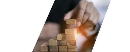 Businessman planing and strategy putting wooden blocks risk or success project stack of hands playing challenge game building construction protect at office of panoramic copy space web banner.の写真素材