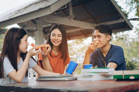 Asian young group together eating pizza in breaking time having fun and enjoy party italian food slice,drinking carbonated with cheese delicious.の写真素材