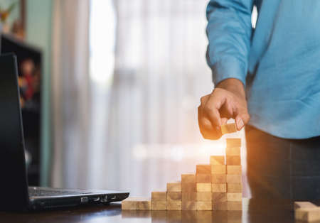 Hand of businessman pulling wooden block before fail on building tower at home and drape change, choice business risking dangerous project plan failure constructionの写真素材