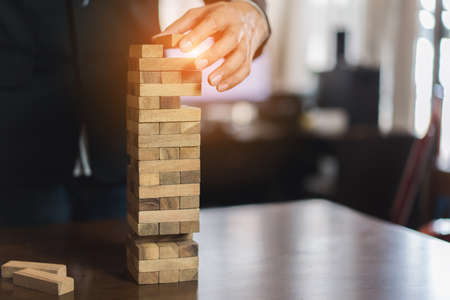 Businessman of pulling wooden block before fail on building tower at home and change, choice business risking dangerous project plan failure constructionの写真素材