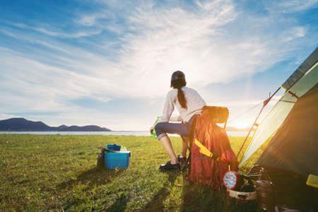 Woman camping and backpack travel sitting relax alone with drinks beer,water for refreshing active...
