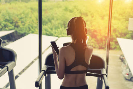 Woman exercise running workout listening music with headphone using smartphone with cardio and...