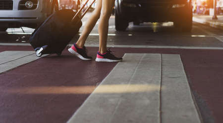 Closeup legs of woman walking step on steert at airport holding suitcase for travel near city, girl happy lifestyle relaxation.の写真素材