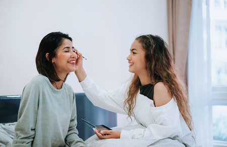 Happy Family teenage daughter is makeup to the mother in the bedroom in the morning before working.の写真素材