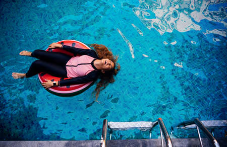 Young girl happy swimming pool on watermelon rubber ring relaxing vacation enjoying on summer season, Top view.の写真素材