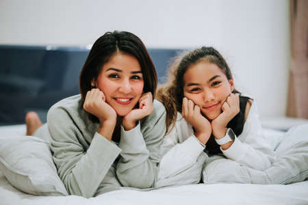 Mom and teenage daughter Happy family lying on bed her smile together at home during the holidays.の写真素材