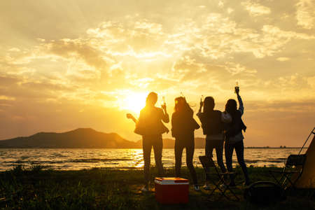 Silhouette Group of women party and dancing with drink bottles enjoy travel camping,trekking in vacation time at sunset.の写真素材