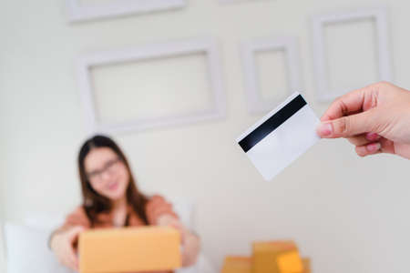 Woman using credit card for easy shopping online delivery with laptop computer at home.