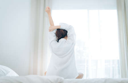 Woman wake up rear view at moring her stretch on bed at home.の写真素材