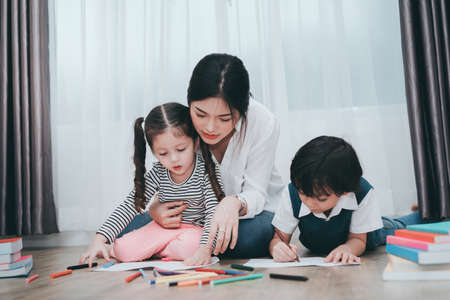 Kindergarten and preschool Kids and teacher or mother helping son and daughter drawing,painting on paper learning art colorful education.の写真素材