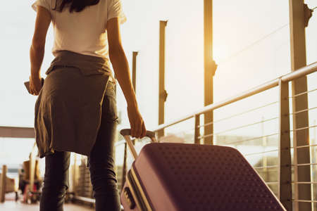 Woman traveler waiting airplane after booking ticket flight at airport with carrying,backpack,suitcase luggage for tranport travel international vacation time in holiday relaxation.の写真素材