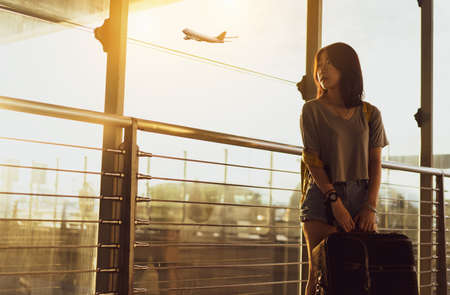 Asian woman traveler waiting airplane after booking ticket flight at airport with carrying,backpack,suitcase luggage for tranport travel international vacation time in holiday relaxation.の写真素材