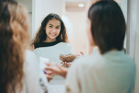 Mom and teenage daughter face wash cleansing with foam in bathroom every day at morning before go to work and study.の写真素材