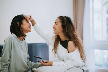 Happy Family teenage daughter is makeup to the mother in the bedroom in the morning before working.の写真素材