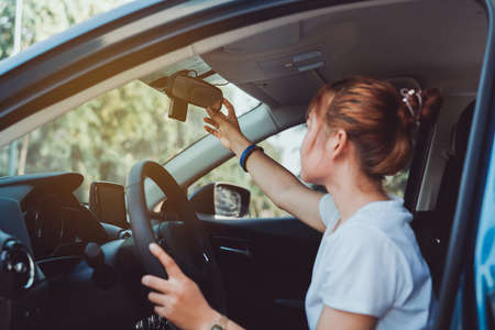 Safety driving woman adjust the car rearview mirror in interior before start travel trip every time.の写真素材