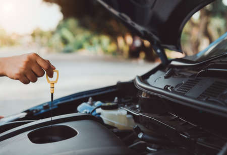 Self service hand use dipstick checking engine oil level car vehicle,professional women maintenance and repair before travel transportation for safety driving on street road.の写真素材