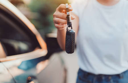 Close up woman holding new car systems key of blue hatchback car after buying from dealer at outdoor.の写真素材