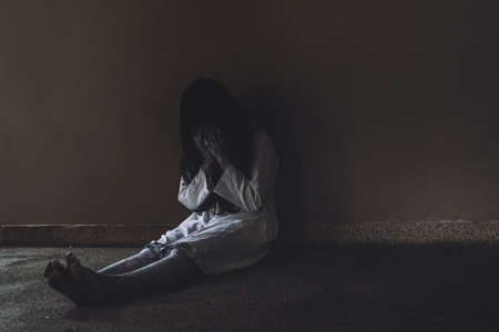 Ghost Woman Horror scene Death movie with Halloween Makeup crying on Floor in Darkroom.の写真素材