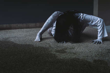 Ghost Woman Horror scene Death movie with Halloween Makeup lying on Floor in Darkroom.の写真素材