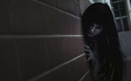 Ghost Woman Horror scene Death movie with Halloween Makeup holding side wall in Darkroom.の写真素材