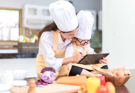 Professional Chef asian mom teaching little son list menu cooking salad vegetable prepare healthy food in the kitchen room for dinner at home happy family lifestyle.の写真素材