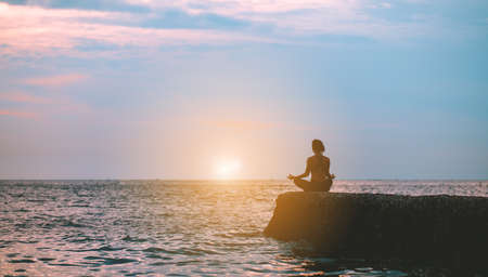 Silhouette yoga woman practice at beach relaxation in class exercise with pose fitness sport for healthy lifestyle and seaside freedom vacation at sunset in summer.の写真素材