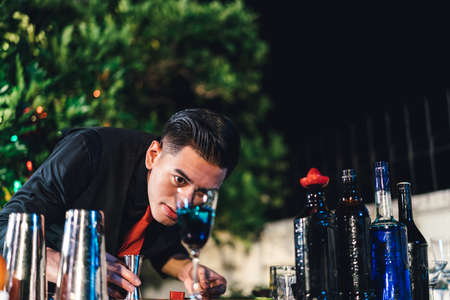 Professional asian male bartender prepare mixing cocktail drink at village night party celebration,...