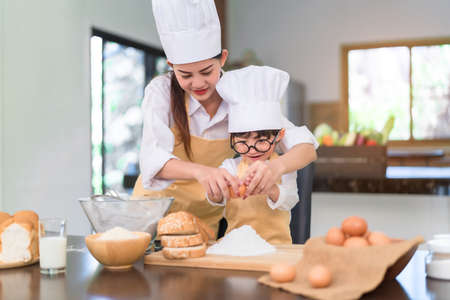 Happy family asian mom and son making bakery cake prepare delicious sweet food in the kitchen room for dinner at home lifestyle.の写真素材
