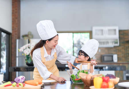 Happy family asian mom teaching little son cooking salad vegetable prepare healthy food in the kitchen room for dinner at home lifestyle.の写真素材