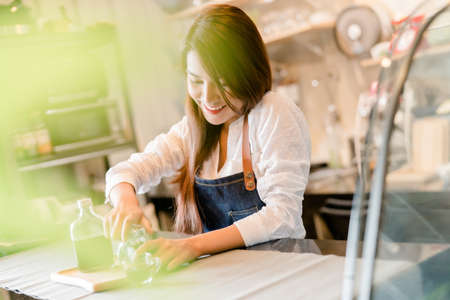 Professional Asian woman Barista preparing coffee at front counter serving coffee cup to customer occupation, part-time, job or owner business working woman happy selling and making drink beverageの写真素材