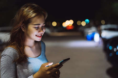Beauty woman looking smartphone mobile phone at night on street her use technology application social media.の写真素材