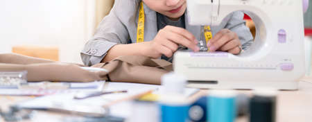 Beautiful asian woman fashion designer tailor fabric working and sewing her service clothes to customer, creative design in studio tailor shop, occupation owner small business conceptの写真素材
