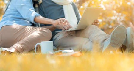 Happy family asian senior couple retirement using laptop computer searching anything in nature park relax vacation time, Elderly romantic valentine lover leisure people lifestyle, Selective focusの写真素材