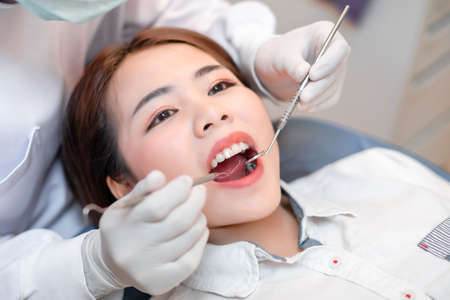 Closeup woman having dental teeth examined dentist check-up via excavator in Clinic her patient for beautiful smileの写真素材