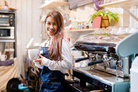 Professional Asian woman Barista preparing coffee at front counter serving coffee cup to customer occupation, part-time,job or owner business working woman happy selling and making drink beverageの写真素材