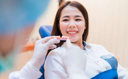 Woman having dental teeth examined dentist check-up with implant false tooth in Clinic her patient for beautiful smileの写真素材