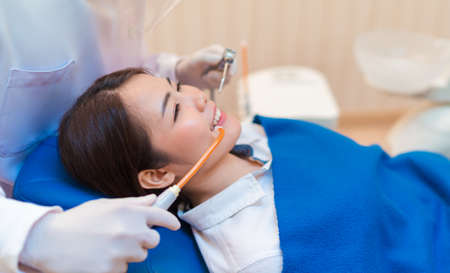 Closeup woman having dental teeth examined dentist check-up via excavator in Clinic her patient for beautiful smileの写真素材