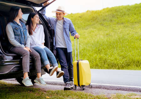 Happy asian group of friends with car travel driving and suitcase at mountain road and street in...