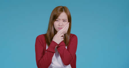 Unhappy young asian woman toothache reaction, Dental healthy concept on blue background isolated studio shotの写真素材
