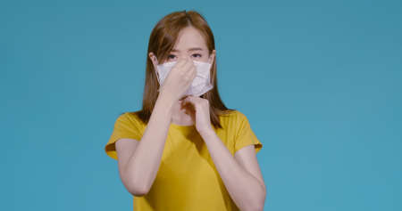 Young asian woman wearing mask protects filter and prevent infection on blue background, Coronavirus covid19, dust pm2.5 healthy conceptの写真素材