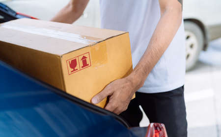 Close-up Delivery man carrying cardboard box for sending to receiver customer by transportation...
