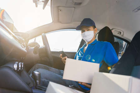 Asian Delivery man wearing mask send a package holding smartphone on front receiver shipping deliver...