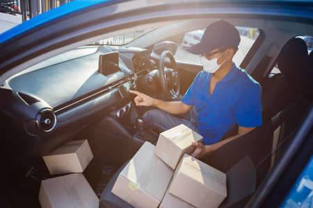 Asian Delivery man wearing mask send a package using smartphone on front receiver shipping deliver...