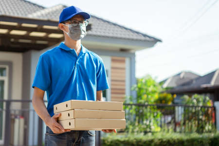 Asian Delivery man wearing mask send pizza from restaurant protection pandemic and fever on front...