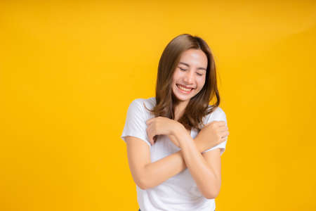 Portrait happy young asian woman feeling carefree laughing positive emotion in white t-shirt, Yellow background isolated studio shot and copy space.の写真素材